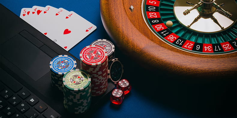 Playing Cards & a Roulette Next to a Laptop